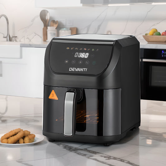 Black Devanti air fryer on a kitchen counter with a plate of food in the foreground.