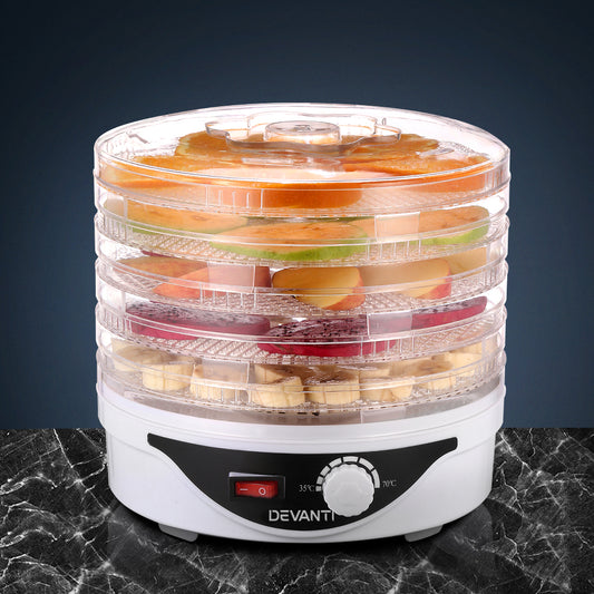 Food dehydrator with stacked trays of sliced fruits on a dark surface