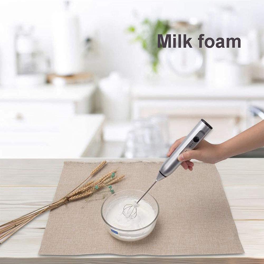 Silver milk frother creating creamy froth in a glass cup
