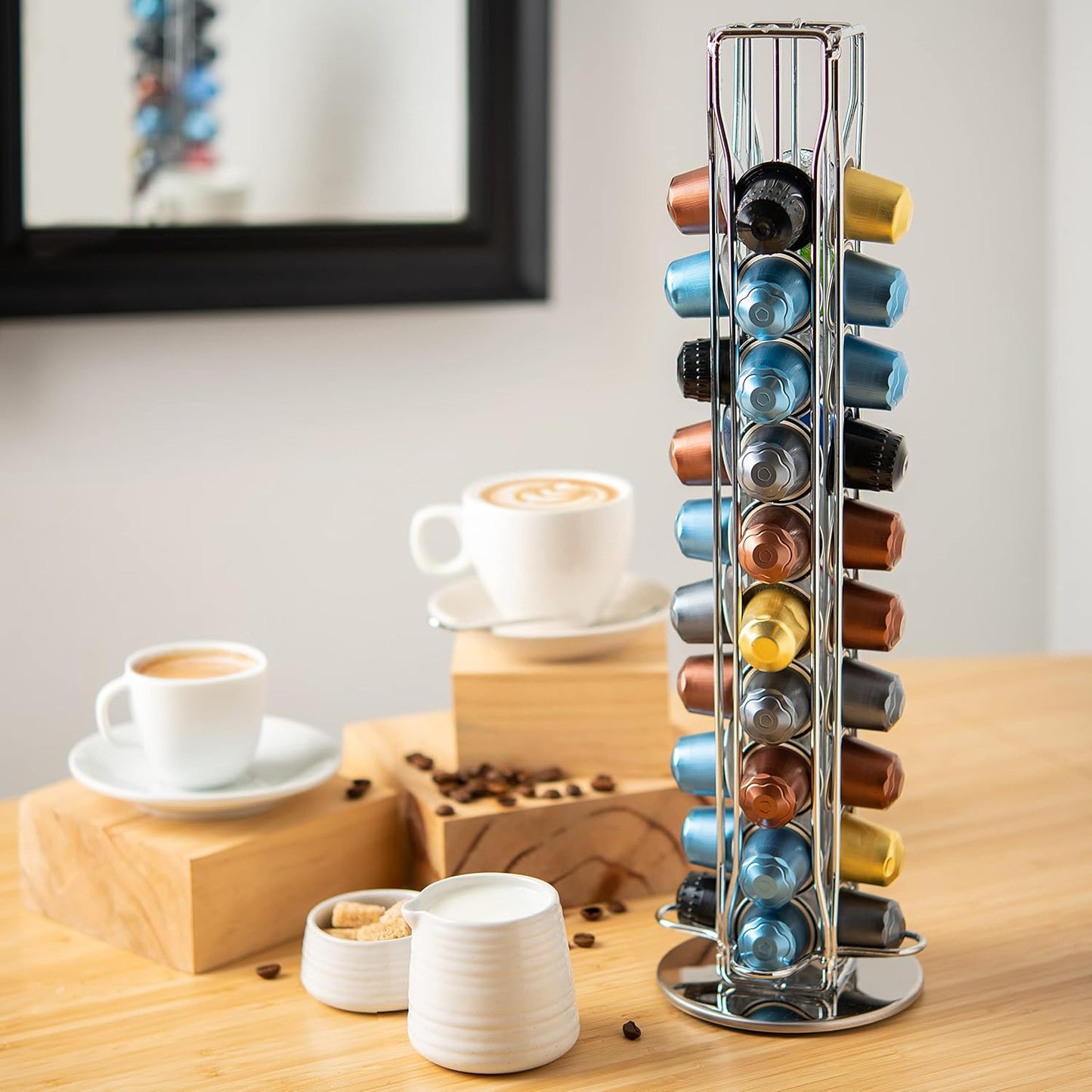 Coffee pod holder with various coffee pods on a wooden table with coffee cups and beans.