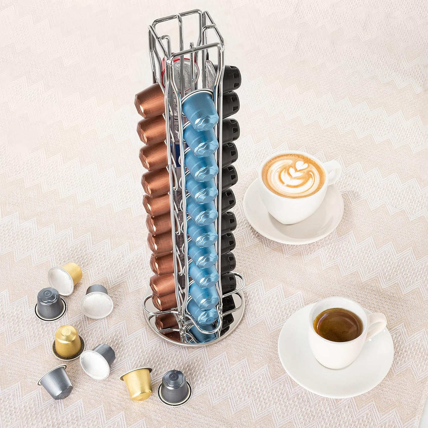 Stackable coffee capsule organizer with various colored capsules on a light surface with two cups of coffee.