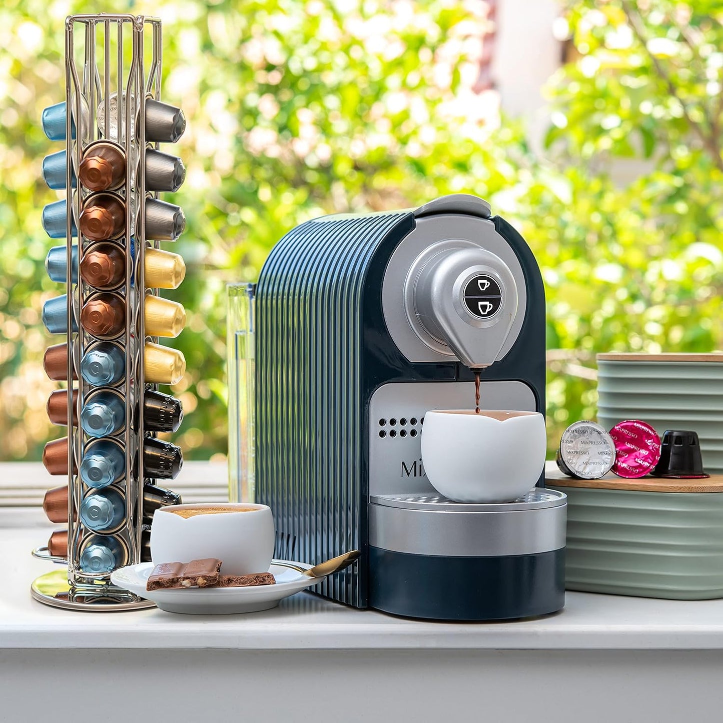 Coffee machine with a cup of coffee and a stack of coffee pods on a table.