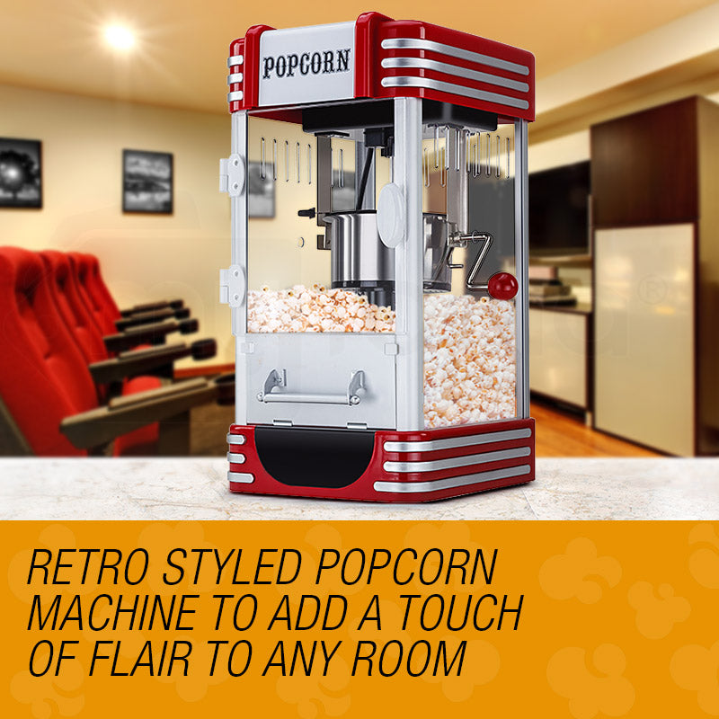 Retro styled popcorn machine on a table with a blurred background of chairs and a counter.