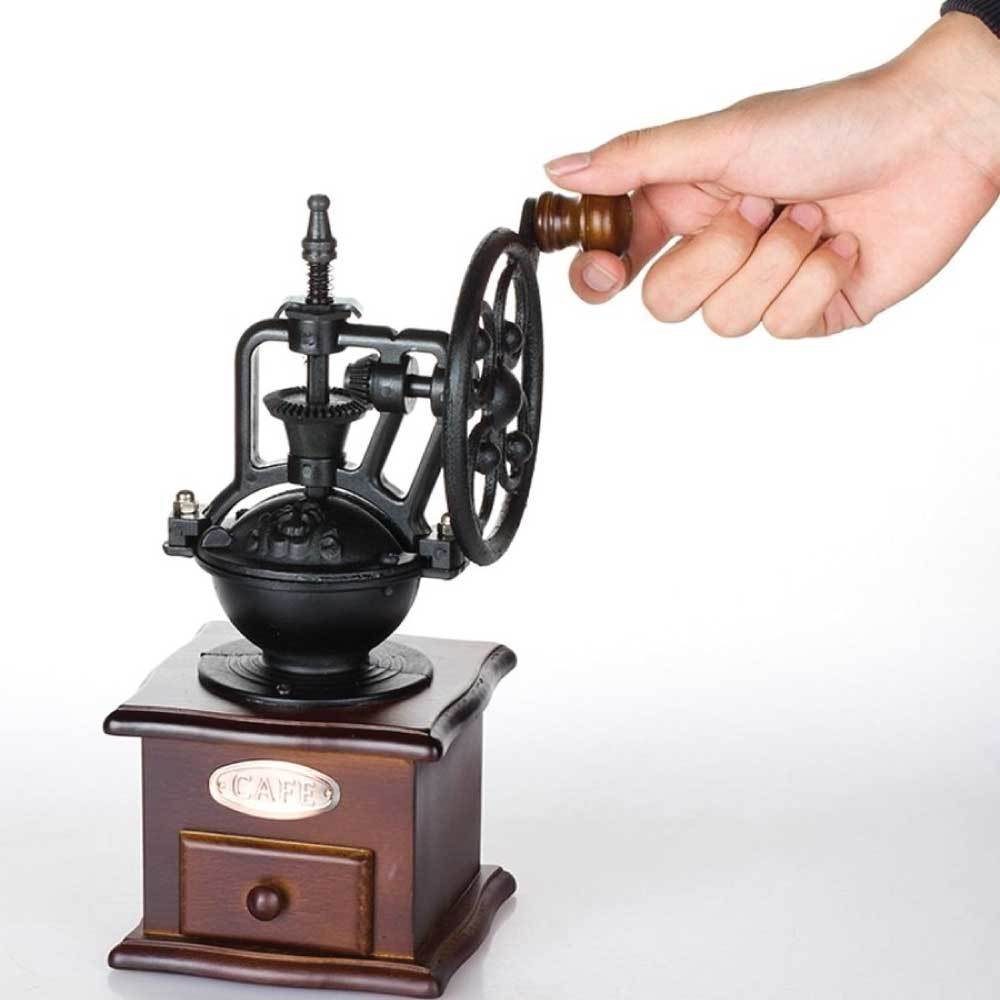 Hand holding a wooden and metal coffee grinder on a white background