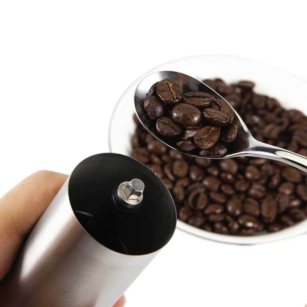 Coffee grinder with a spoonful of coffee beans on a white background