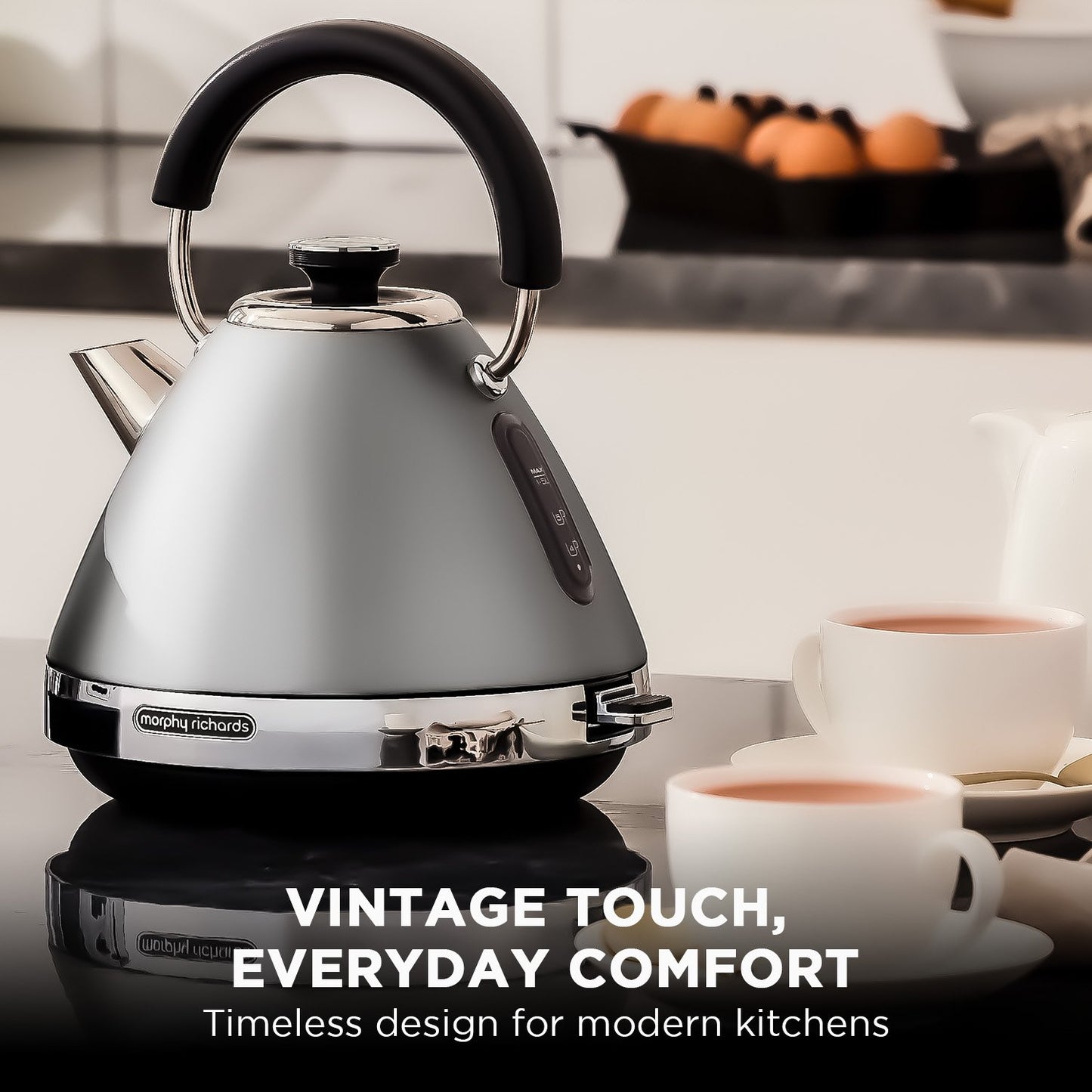 Silver kettle with black handle on a kitchen counter, surrounded by coffee cups.