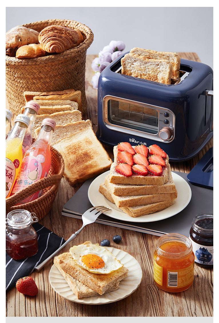 Breakfast setup with toaster, toast, fruits, and drinks on a wooden table.