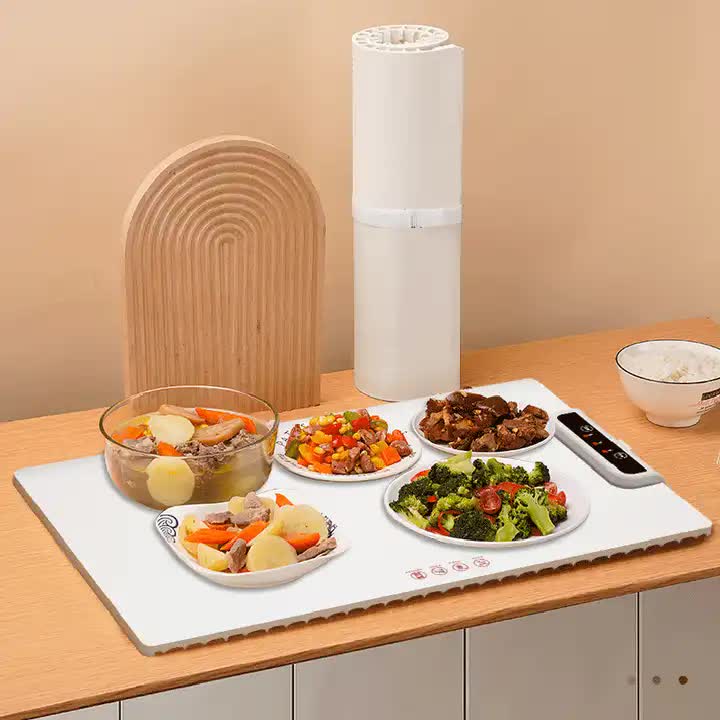 Table with plates of food and a roll of paper towels on a wooden surface.
