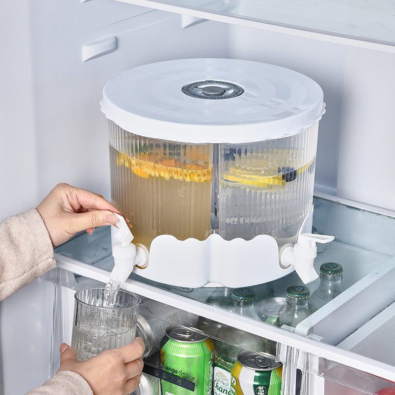 Person using a refrigerator water dispenser with a container of fruit behind it.