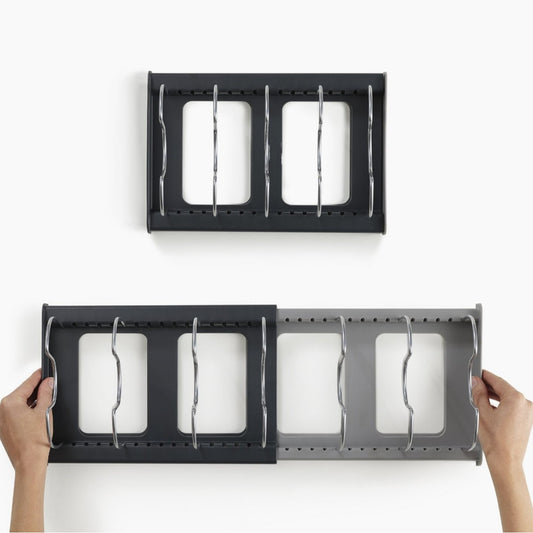Black metal wall hooks with three hooks each held by hands on a white background