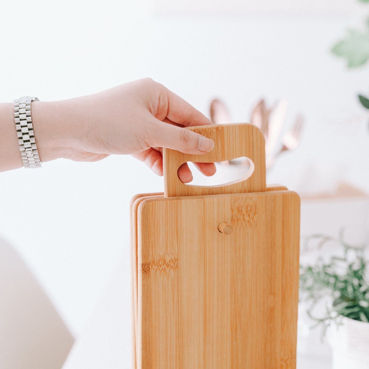 Hand holding a wooden cutting board with a blurred background