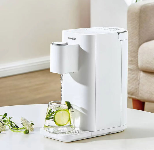 White electric water dispenser pouring water into a glass with lime and mint on a white surface.