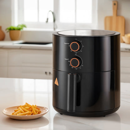 Black air fryer on a kitchen counter with a plate of fries