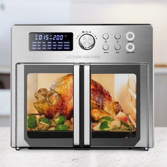 Stainless steel Kitchen Couture oven with two cooking racks showing roasted chicken and vegetables.
