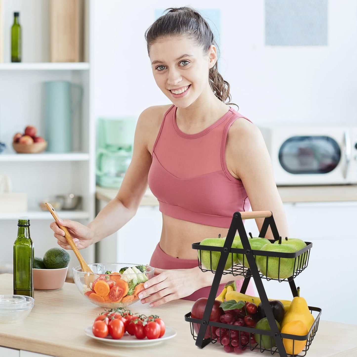 Woman in a kitchen preparing a salad with fruits and vegetables.