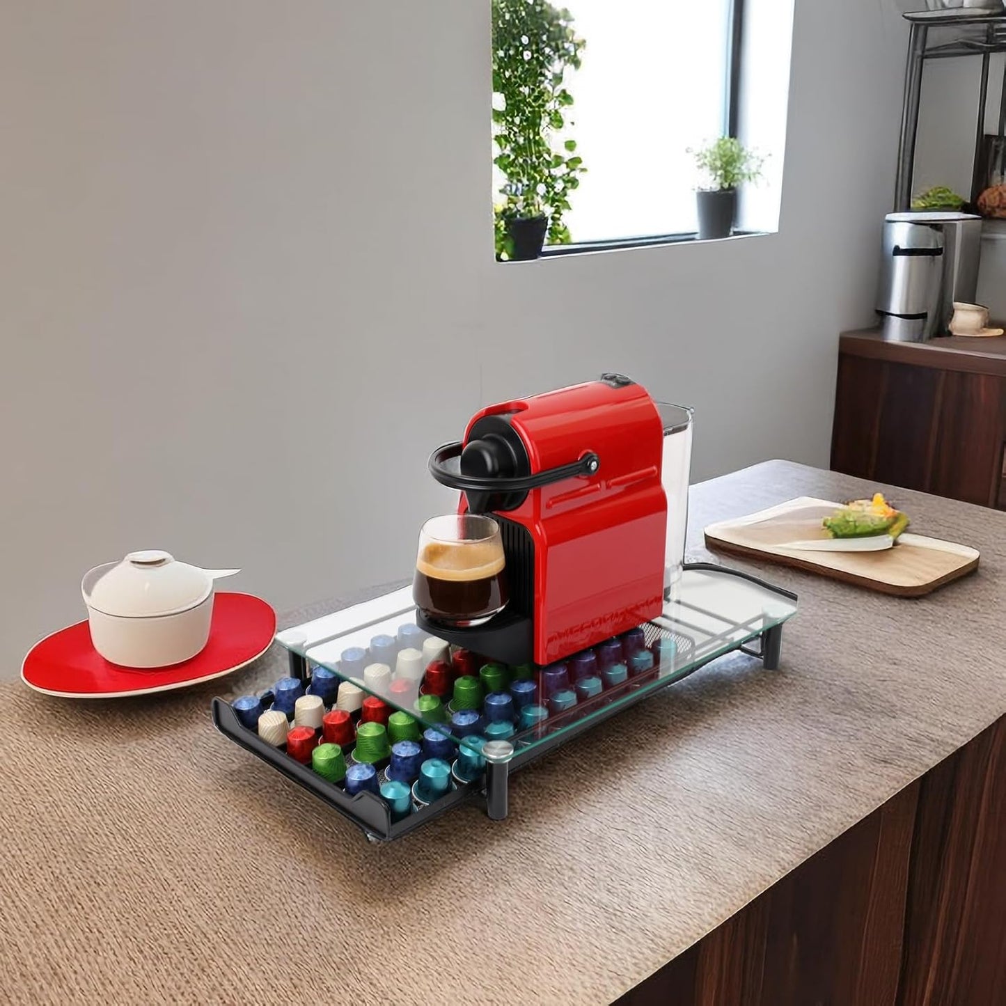 Red coffee machine on a counter with colorful capsules and a glass of coffee.
