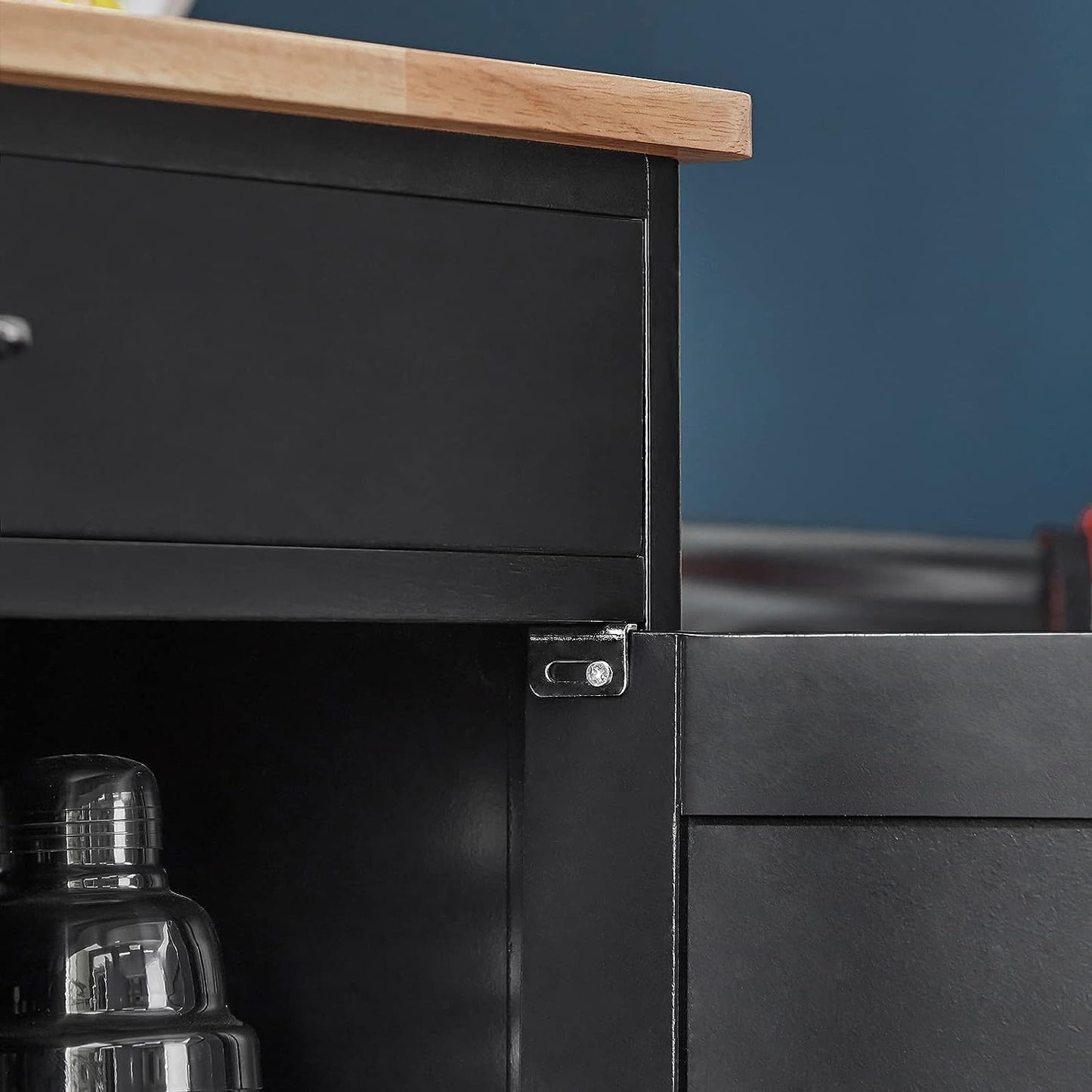 Close-up of a black cabinet with a wooden top against a blue wall.