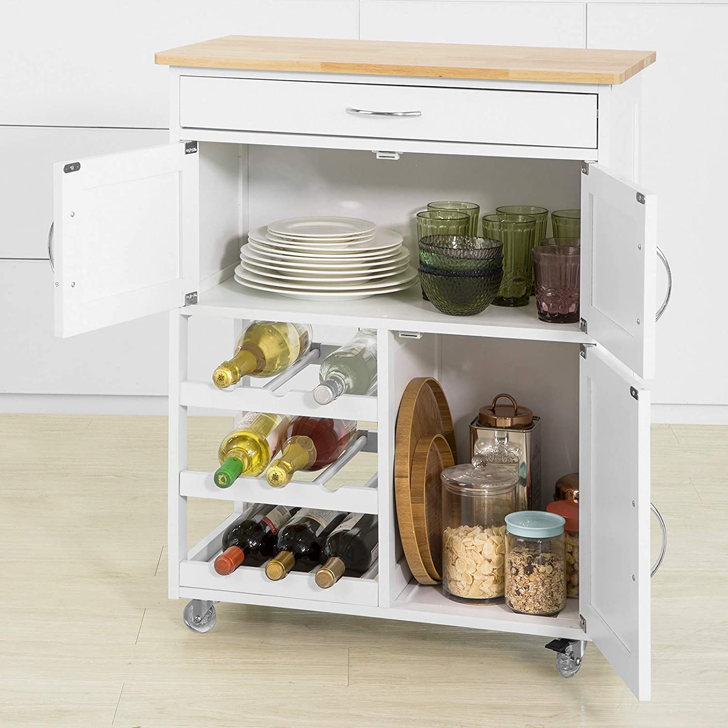 White kitchen cart with wooden top, shelves filled with plates, glasses, bottles, and jars.
