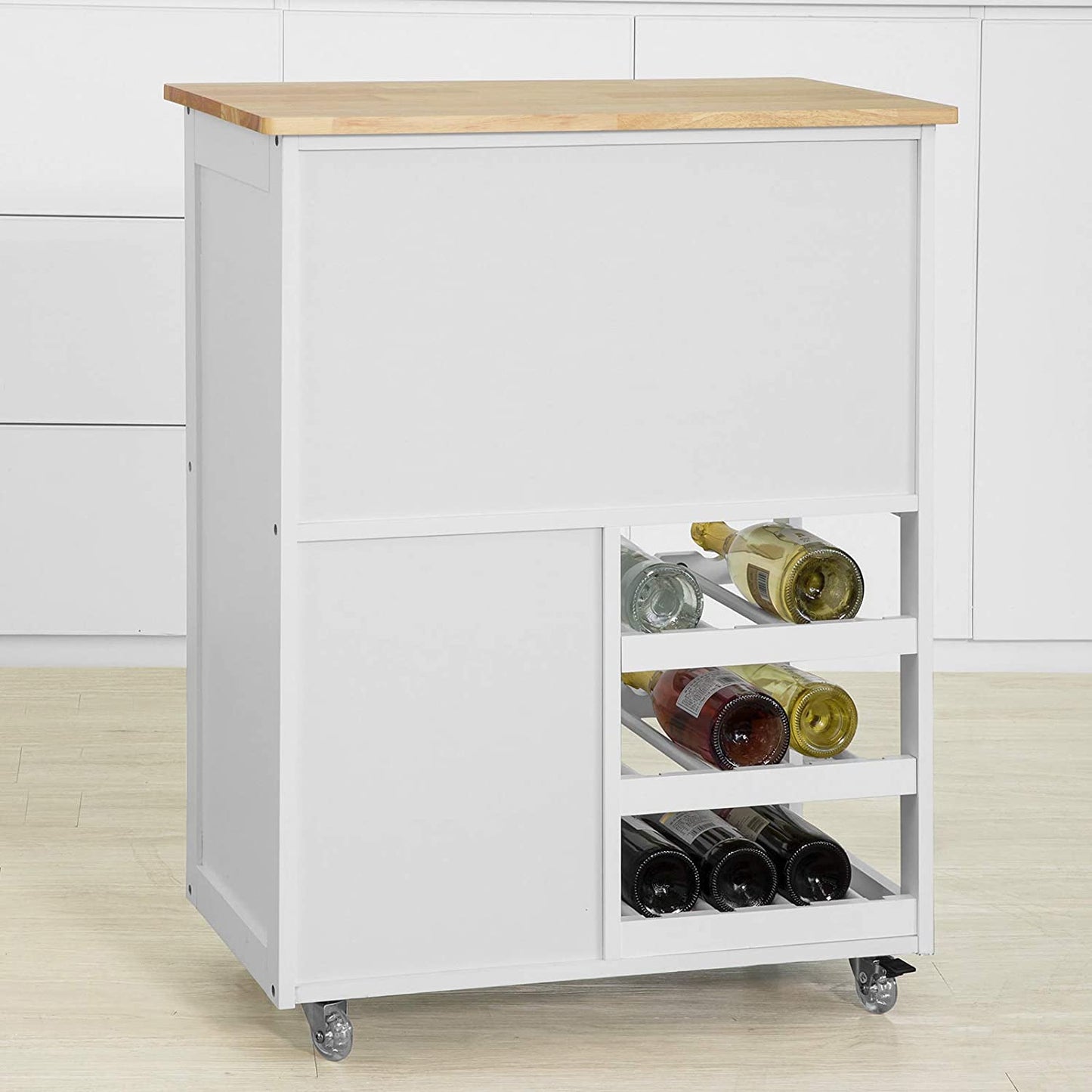 White kitchen island with wooden top and wine storage on wheels against a white wall.