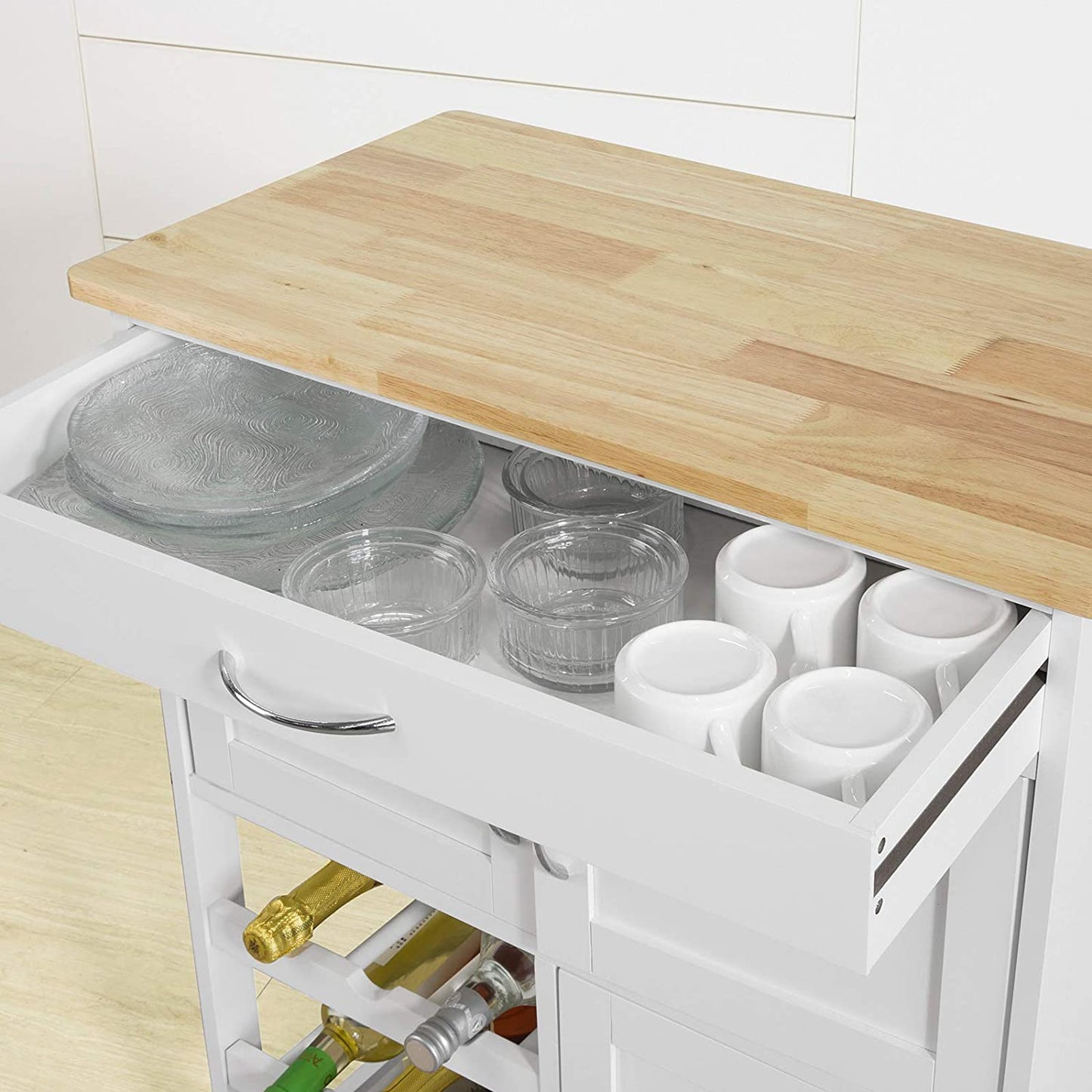 Kitchen island with open drawer containing glasses and cups, wooden countertop.