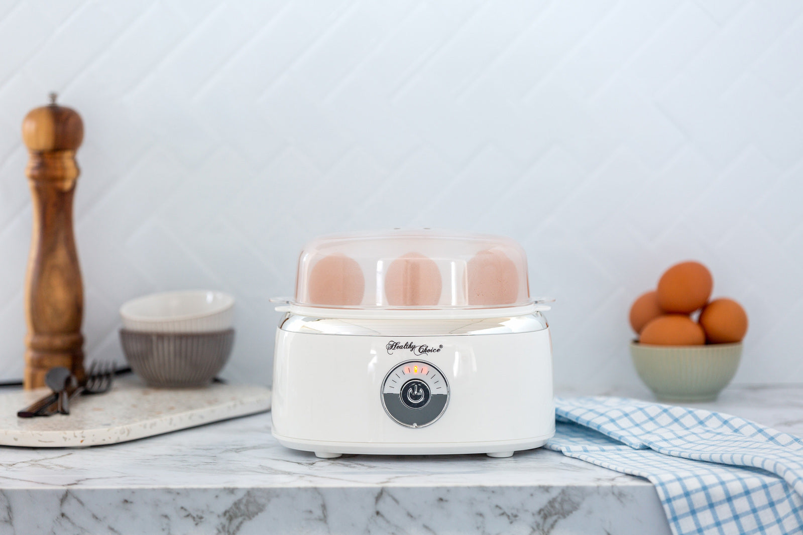 White yogurt maker on a kitchen counter with eggs and kitchen items in the background