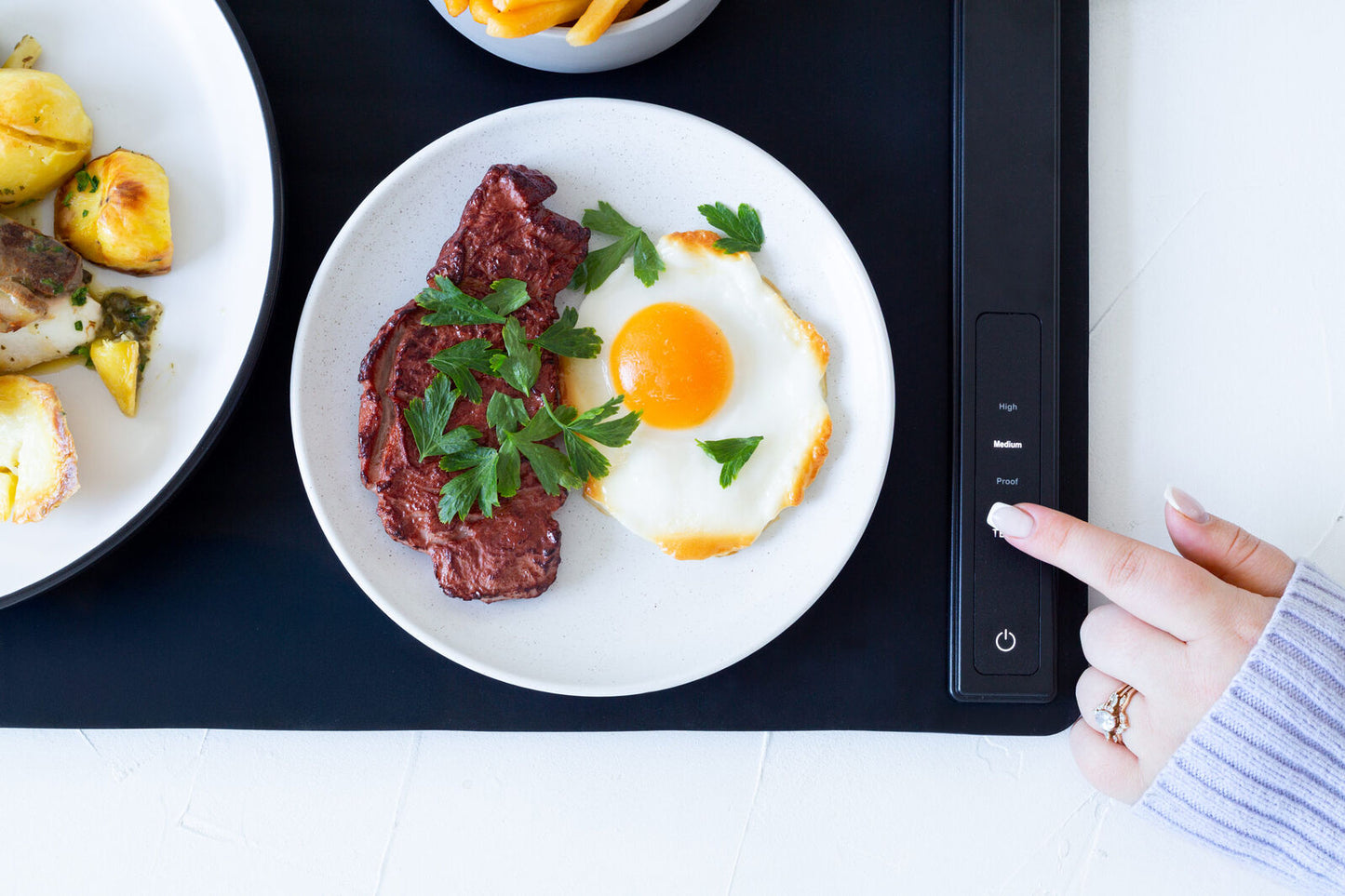 Plate of steak and eggs on a digital display, with a hand interacting with the device.
