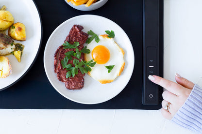 Plate of steak and eggs on a digital display, with a hand interacting with the device.