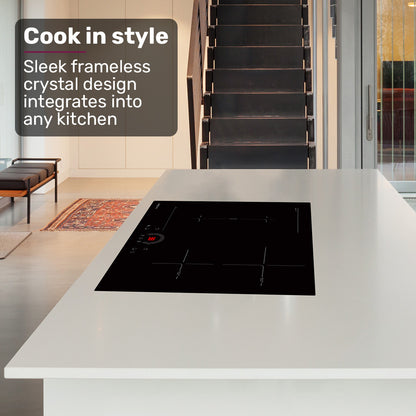 Modern kitchen with a black glass cooktop on a white countertop, featuring text about frameless crystal design.