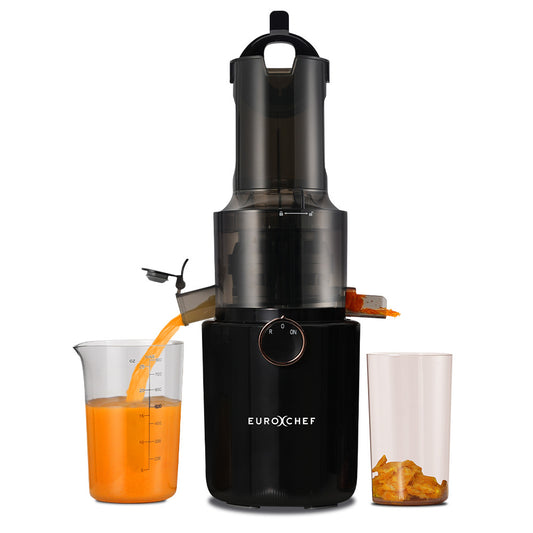 Black juicer with carrot juice being poured into a glass container on a white background