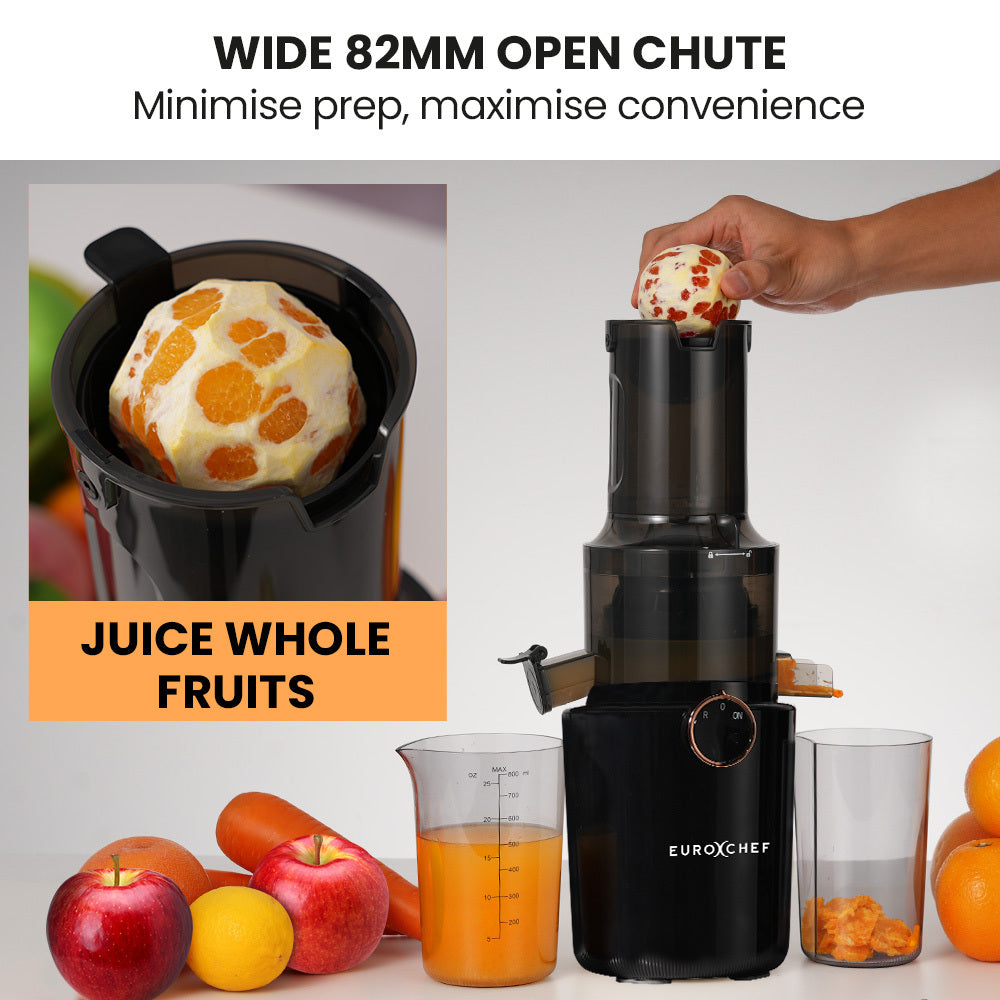 Black juicer with a wide 82mm open chute, surrounded by fruits and a glass of juice.