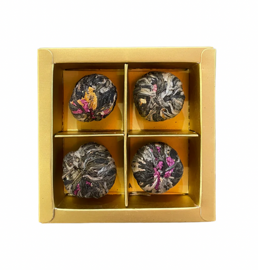 Four tea balls in a gold box on a white background