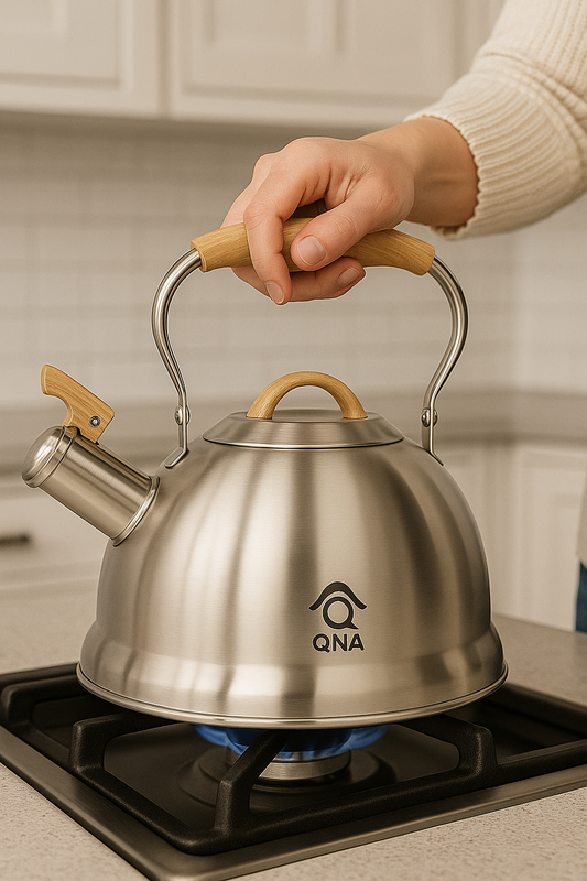 Stainless steel kettle with wooden handles on a gas stove, brand 'QNA' visible