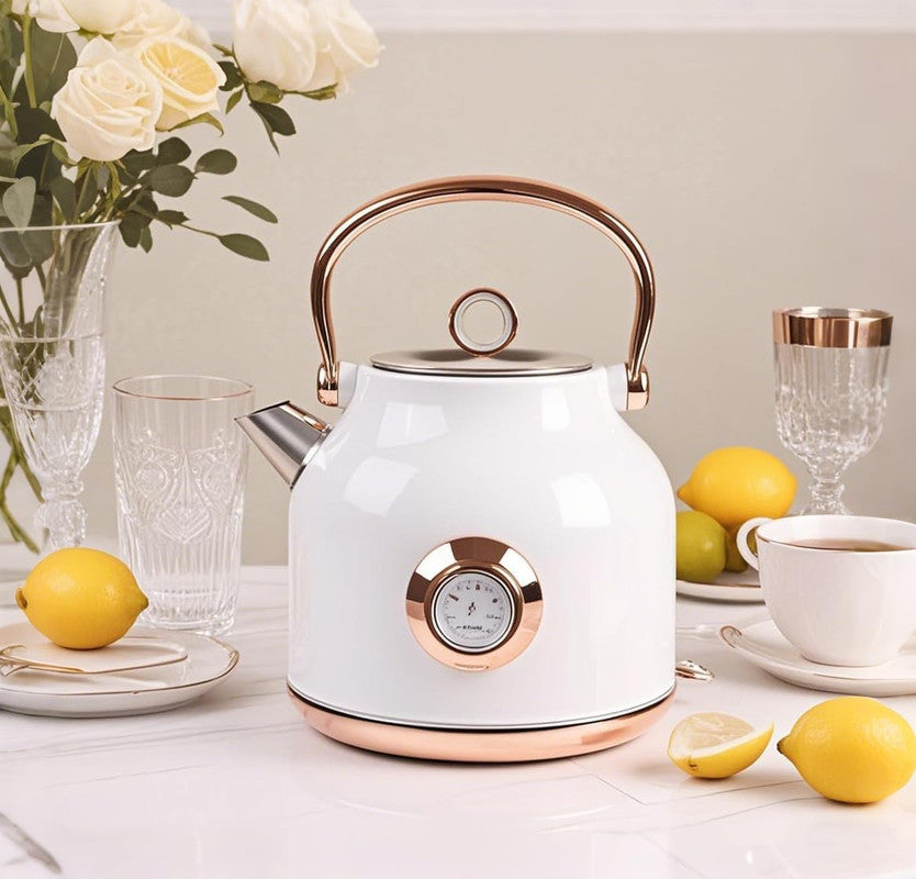 White electric kettle with rose gold accents on a table with lemons and tea.