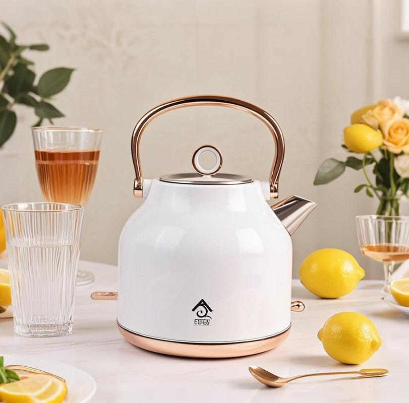 White electric kettle with rose gold handle on a table with lemons and glasses.