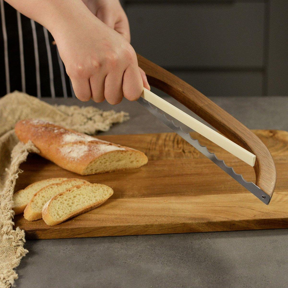 Person using a bread knife on a wooden cutting board with sliced bread