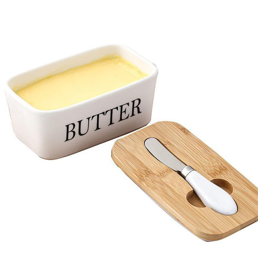 Butter dish with a wooden cover and knife on a white background
