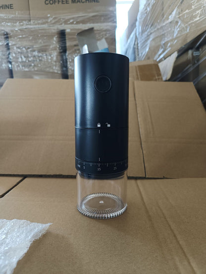 Black and clear pepper grinder on a cardboard surface with boxes in the background