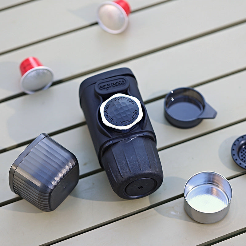 Black and red coffee pod on a wooden surface with a metal cup of coffee.