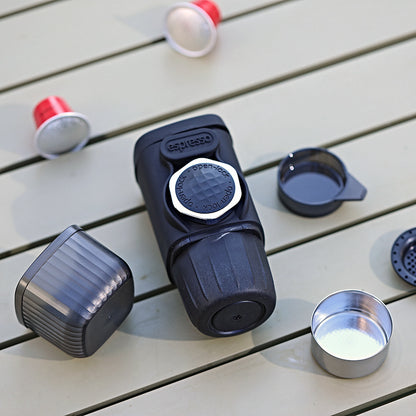 Black and red coffee pod on a wooden surface with a metal cup of coffee.