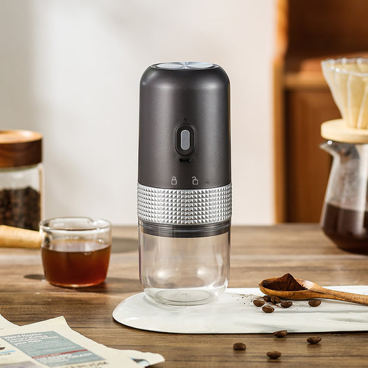 Black and silver coffee maker on a wooden table with coffee beans and a glass of liquid.