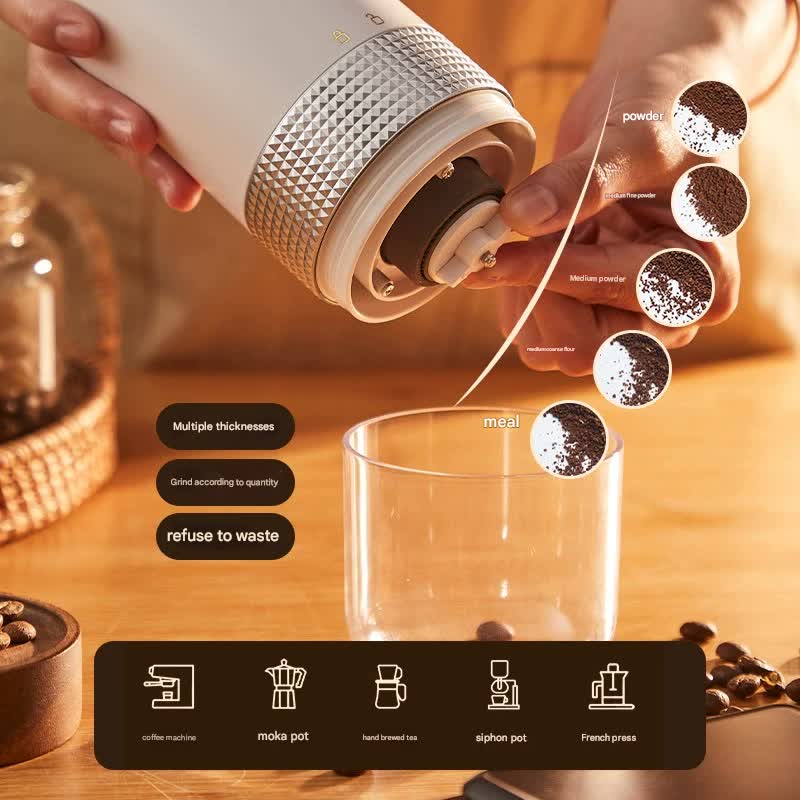 Person using a manual coffee grinder to grind coffee beans into a glass mug on a wooden surface.