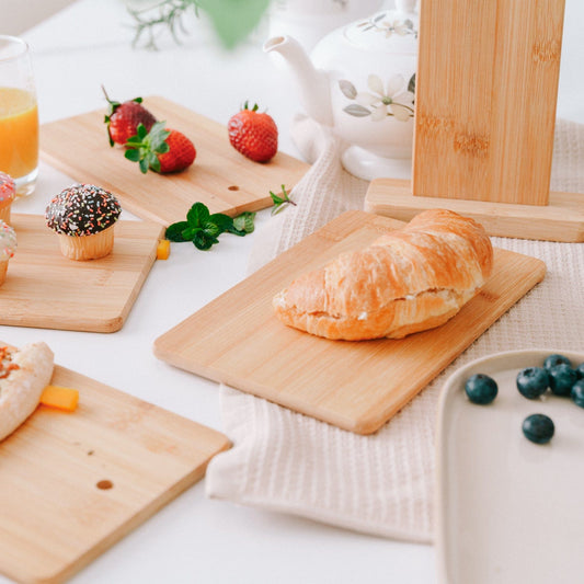 Wooden cutting boards with pastries and fruits on a white tablecloth