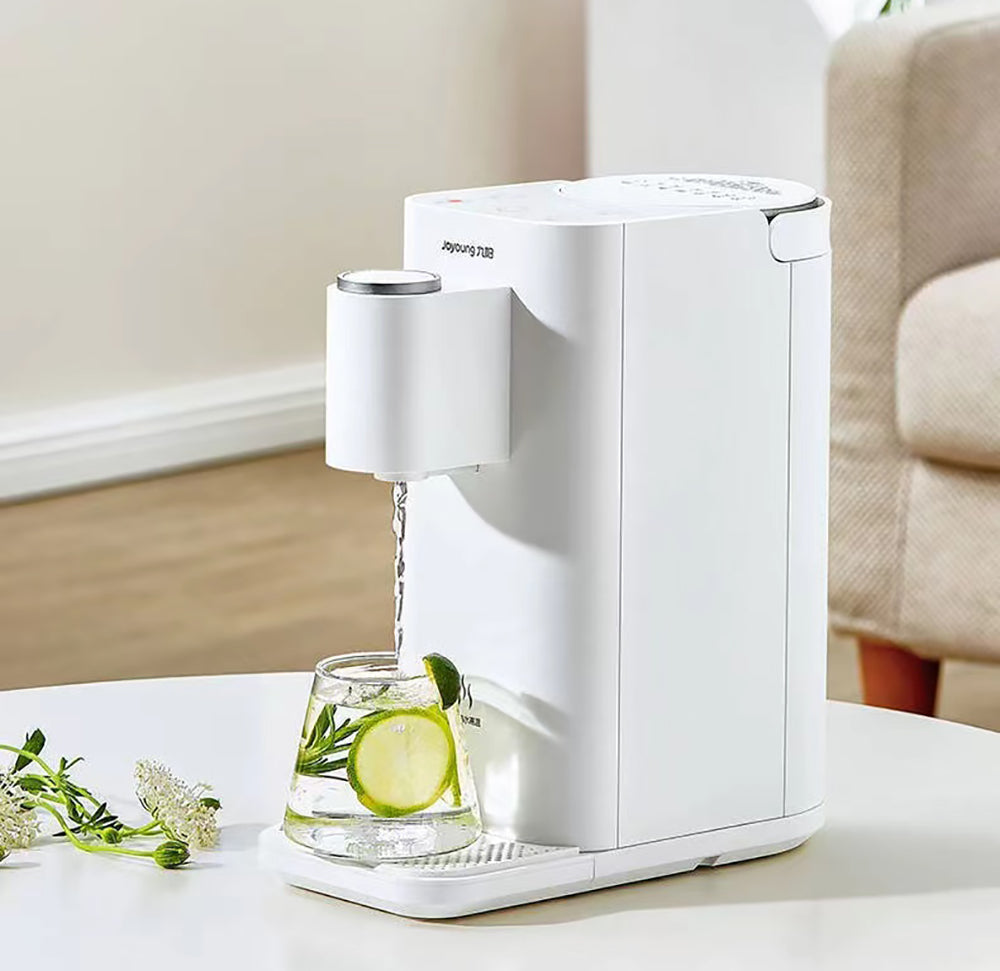 White electric water dispenser pouring water into a glass with lime and mint on a white surface.