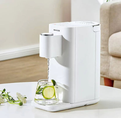 White electric water dispenser pouring water into a glass with lime and mint on a white surface.
